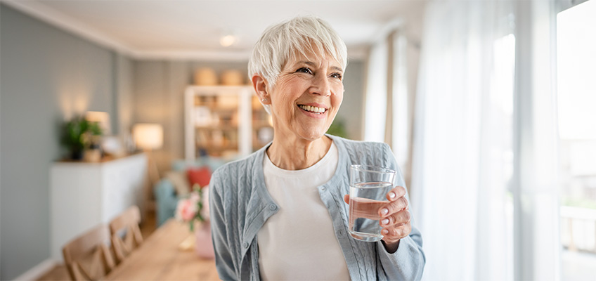 A senior woman holding a glass of water.
